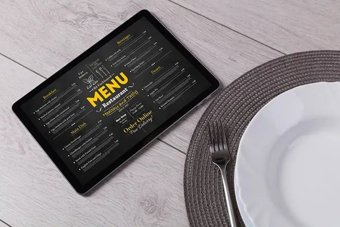 Online order menu on a tablet beside an empty plate and tableware