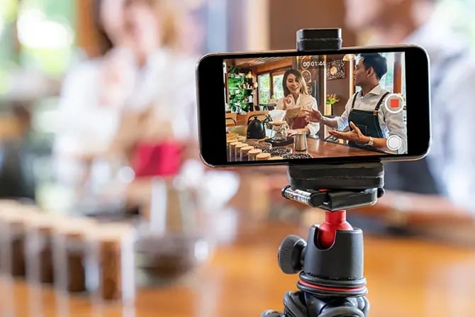 Restaurant owner recording video content with smartphone in cafe for a Google Ad campaign.