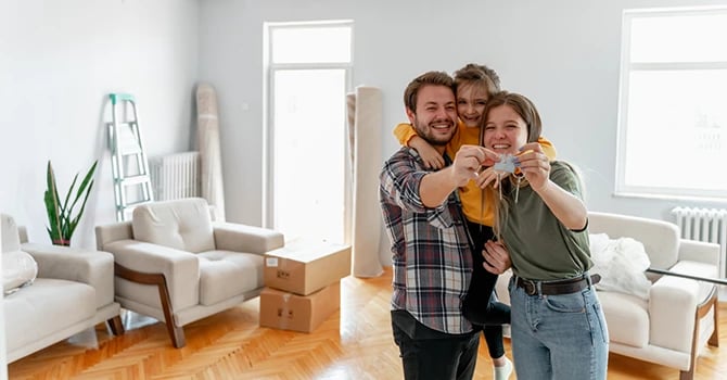 Excited young family of new movers show keys to their new apartment.