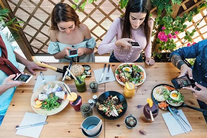 Restaurant diners taking food pictures with mobile smartphones to share on a social media account.