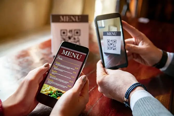 A couple scanning the QR code to view the menu on a restaurant website.