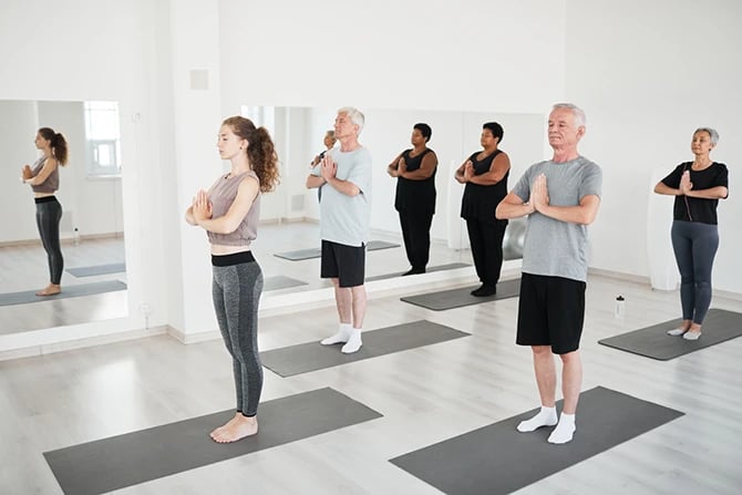 Group of people with eyes closed during yoga class in a local fitness studio.