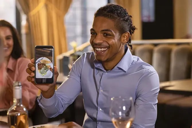 A man showing his friends a photo of the food he has taken on his smartphone.