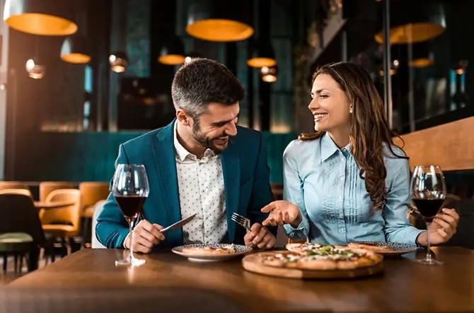 Cheerful couple eating pizza together and having fun in a restaurant.