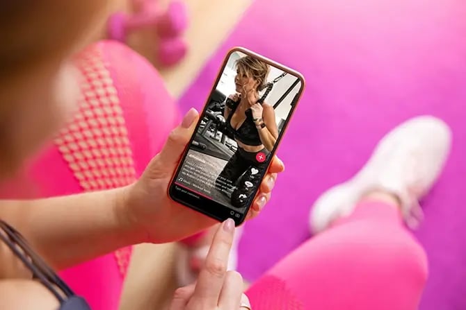 Woman looking at an influencer’s fitness videos shared on social media.