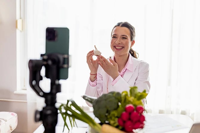 A female nutritionist in a lab coat recording a video blog for a social media platform.