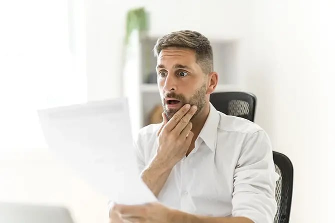 A worried middle-aged man reading an unexpected paper document.