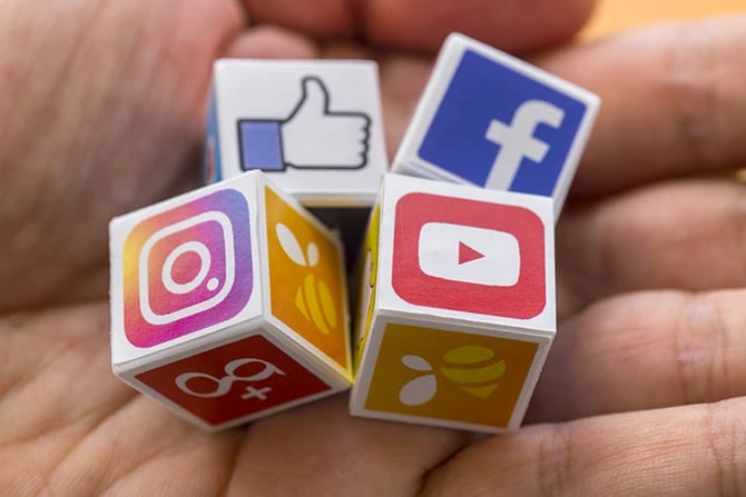 Cubes with popular social media services icons, including Facebook, Instagram, Youtube on a hand